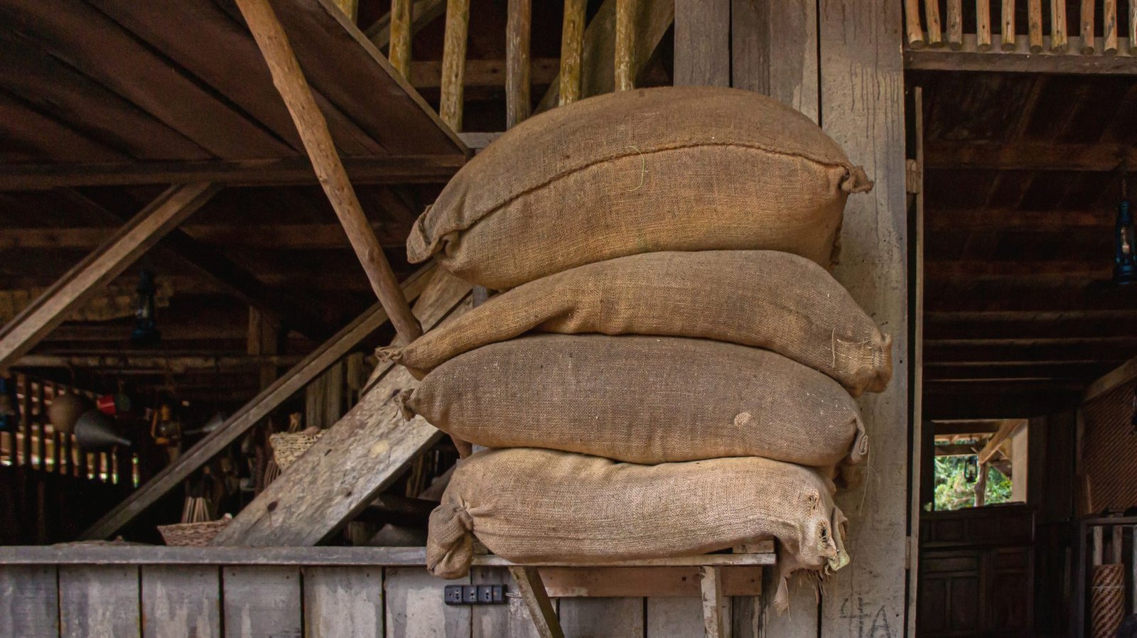 Burlap feed sacks stacked on a loft in a wooden barn.